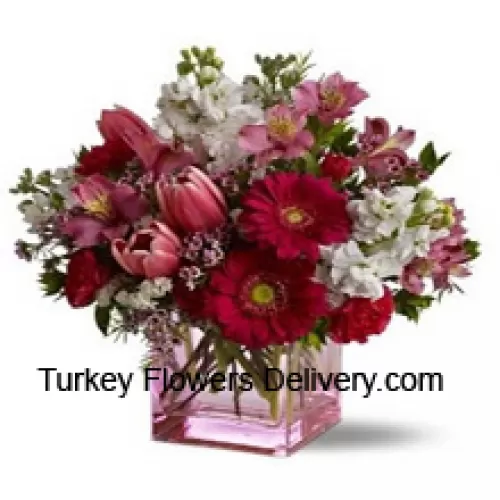 Rose rosse, tulipani rossi e fiori assortiti con riempitivi stagionali disposti in modo splendido in un vaso di vetro