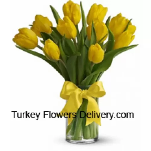 Gelbe Tulpen mit saisonalen Füllern und Blättern in einer Glasvase - Bitte beachten Sie, dass im Falle der Nichtverfügbarkeit bestimmter saisonaler Blumen diese durch andere Blumen von gleichem Wert ersetzt werden.