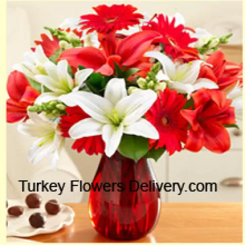Gerbera roșie, crin alb, crin roșu și alte flori asortate aranjate frumos într-o vază de sticlă