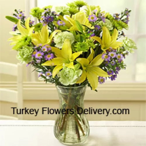 Желтые лилии и другие разнообразные цветы красиво оформлены в стеклянной вазе