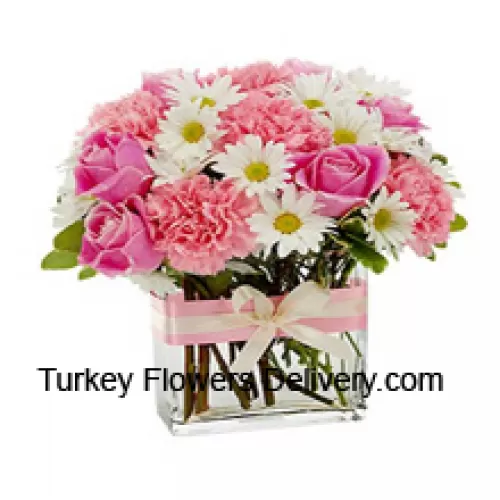 Roze rozen, roze anjers en diverse witte seizoensbloemen prachtig gerangschikt in een glazen vaas