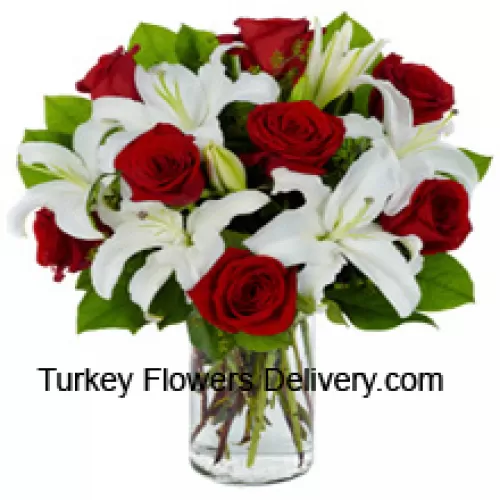 红玫瑰和白百合与季节性填充物放在玻璃花瓶中