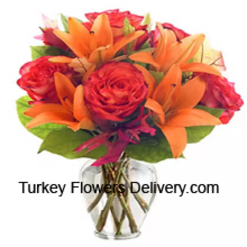 Оранжевые лилии и оранжевые розы с сезонными наполнителями красиво оформлены в стеклянной вазе