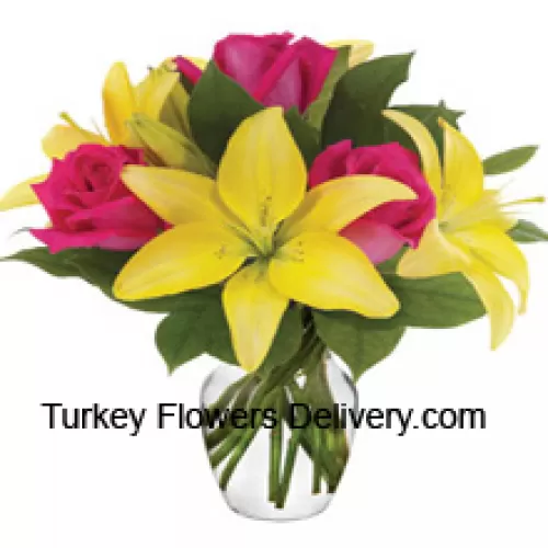 Róże różowe i lilie żółte z dodatkiem sezonowych wypełniaczy uroczo ułożone w szklanym wazonie