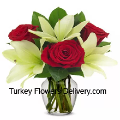 Czerwone róże i białe lilie z sezonowymi dodatkami w szklanej wazonie