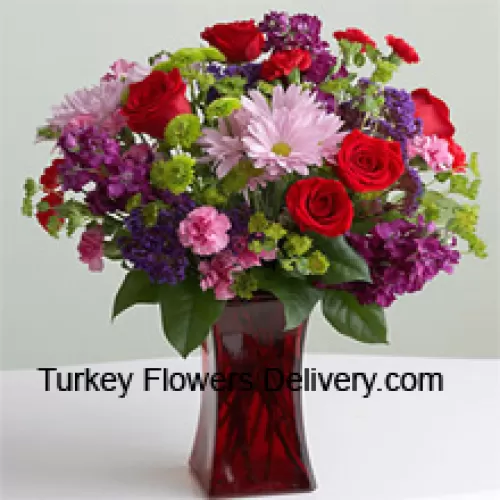 赤いバラ、ピンクのカーネーション、その他季節の花々がガラスの花瓶に入ったアレンジメントです