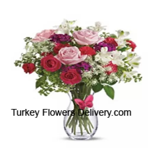 Punaisia ruusuja, vaaleanpunaisia ruusuja, punaisia neilikoita ja muita assortoituja kukkia täytteiden kera lasimaljakossa -- 24 varsia ja täytteitä
