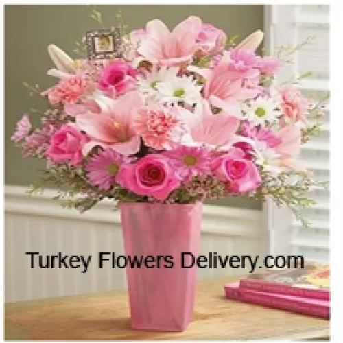 Vaaleanpunaiset ruusut, vaaleanpunaiset neilikat, vaaleanpunaiset gerberat, valkoiset gerberat ja vaaleanpunaiset liljat sesonkikoristeiden kera lasimaljakossa