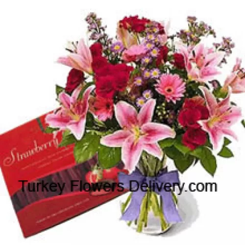 Разнообразные цветы в вазе и коробка шоколада