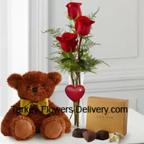 Trei trandafiri roșii cu frunze într-un vas, un ursuleț de pluș maro drăguț de 10 inch și o cutie de ciocolată Godiva. (Ne rezervăm dreptul de a înlocui ciocolata Godiva cu ciocolată de valoare egală în caz deindisponibilitate. Stoc limitat)